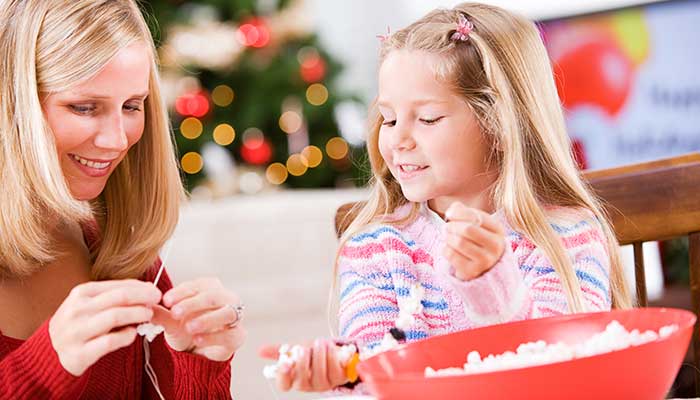 mother and daughter stringing popcorn garland