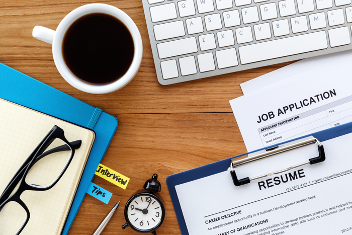 job application and resume sitting on a desk next to a computer