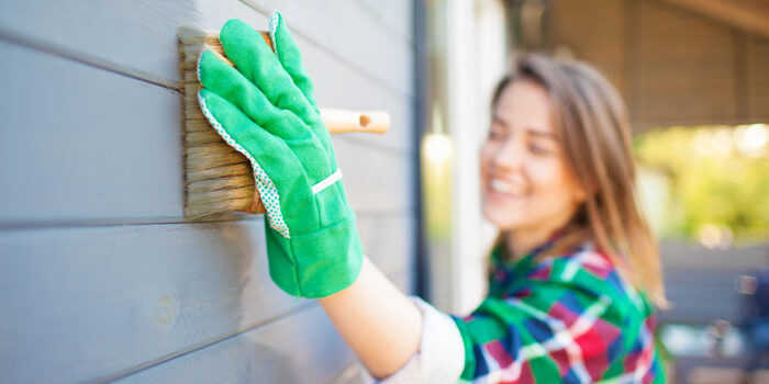 woman painting external siding on her house