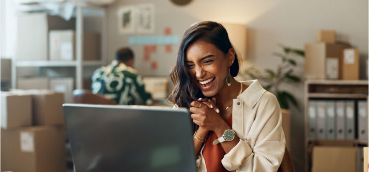 a woman sitting in front of her computer clearly excited about the news she is viewing